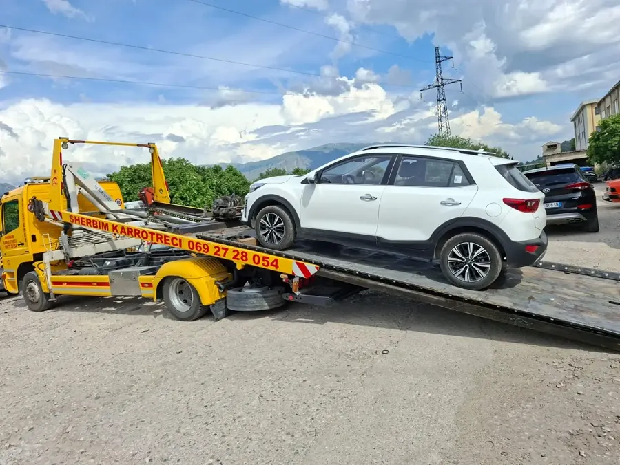 Flatbed tow truck loading a white SUV in a parking lot