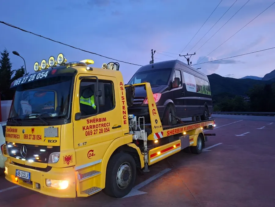 Tow truck with a delivery van loaded, dusk sky in the background
